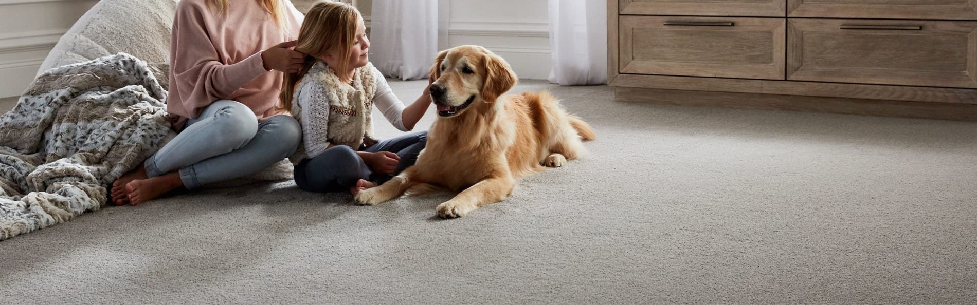 Mother and daughter sitting on carpeted floor with dog